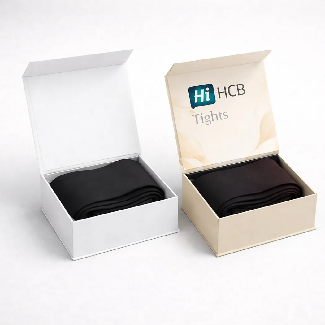 Two luxury magnetic-closure boxes- shown open to reveal folded black tights inside with elegant branding- class=